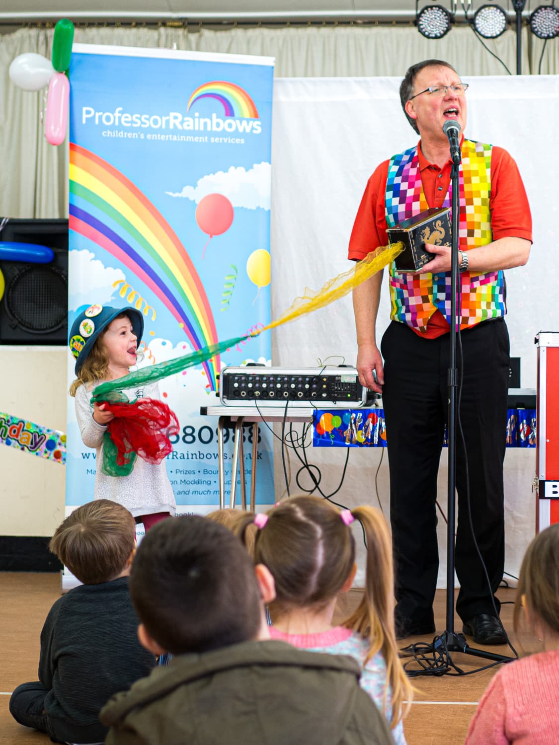 A child pulling colourful silks from a magic box