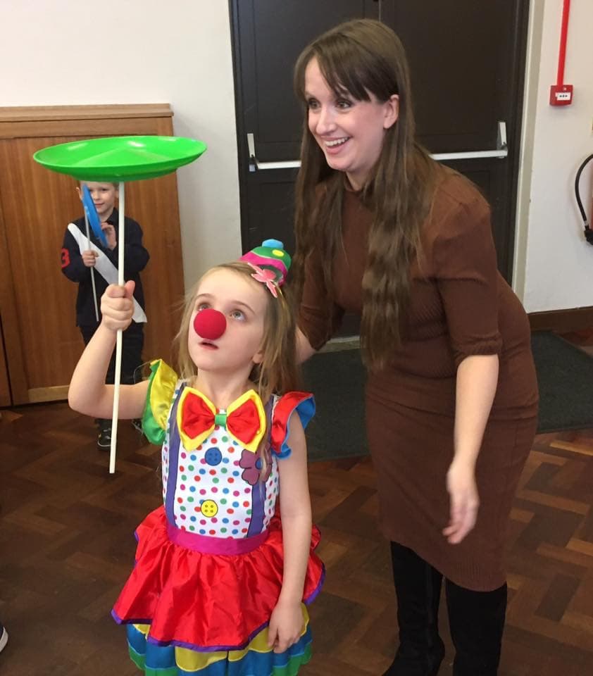 A child dressed as a clown using a spinning plate