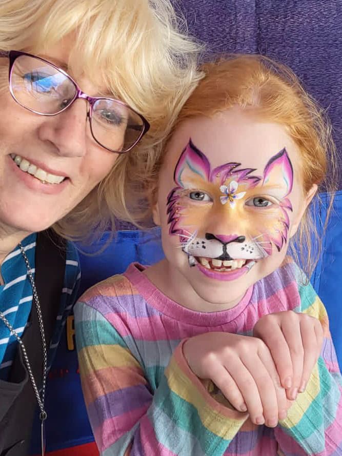 A face painter with a child wearing tiger face paint
